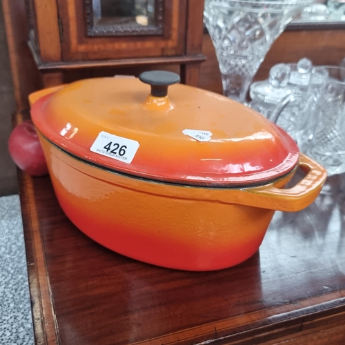 426 - A very heavy large cast iron casserole dish with heatproof handle. Dish is finished with an attracti... 