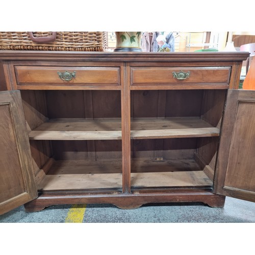 411 - A handsome Edwardian sideboard with two drawers and two cupboards with brass drop handles. Decorated... 