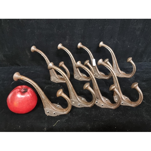 142 - Eight cast metal coat hooks. Designed for wall mounting, with nice patina.