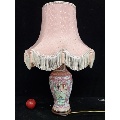 242 - An ornate large table lamp, with famille rose ceramic base. With pink satin shade.