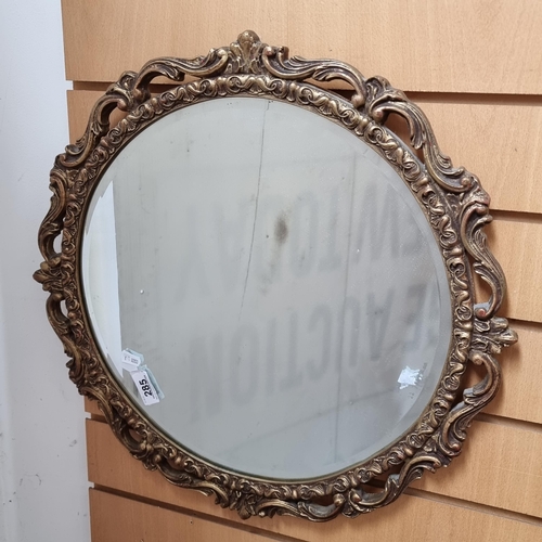 285 - An elegant wall hanging bevelled circular mirror with elaborate gilt wood frame.