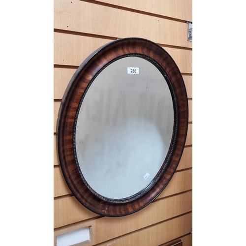 286 - A lovely oval bevelled mirror set into a handsome wooden frame.