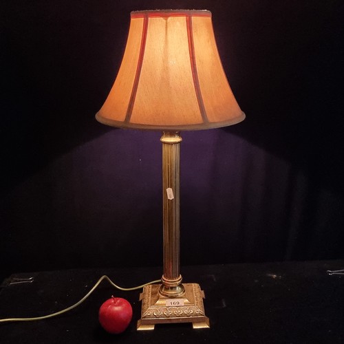 169 - An elegant table lamp with heavy brass base and reeded stem. Topped with a gold  shade.