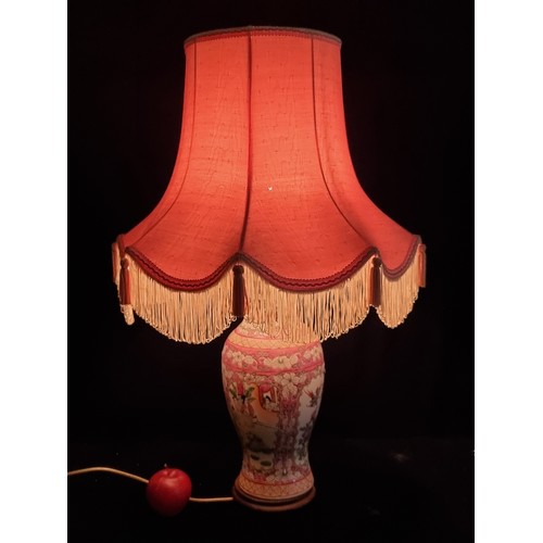 242 - An ornate large table lamp, with famille rose ceramic base. With pink satin shade.