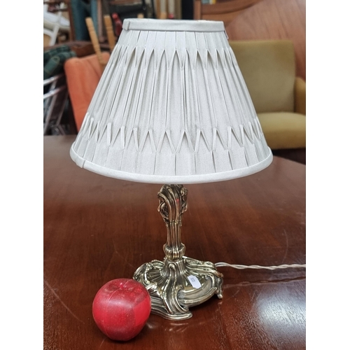 690 - A lovely example of a table lamp with brass stem featuring profuse scrollwork topped with pleated li... 