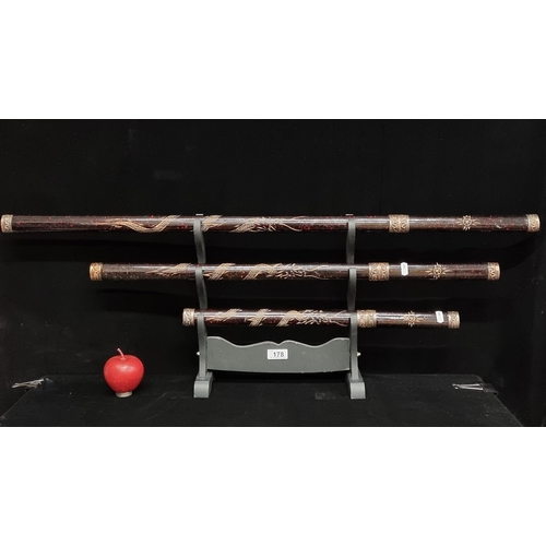 178 - A set of three katana swords in graduating sizes each with ornamental sheath and wooden display unit... 