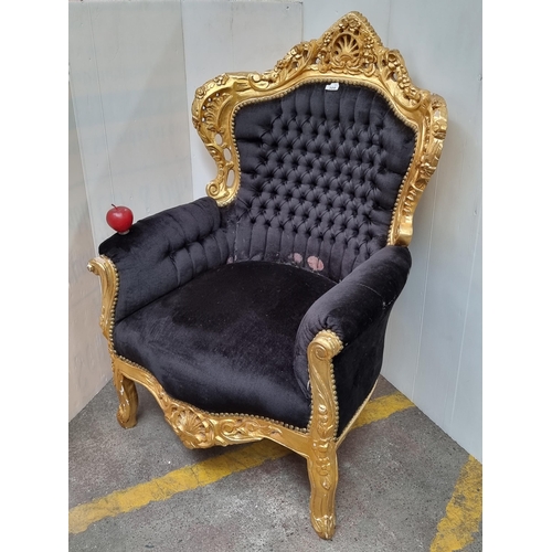 308 - A highly ornate, baroque style throne chair with a gilded carved frame and plush black button back u... 