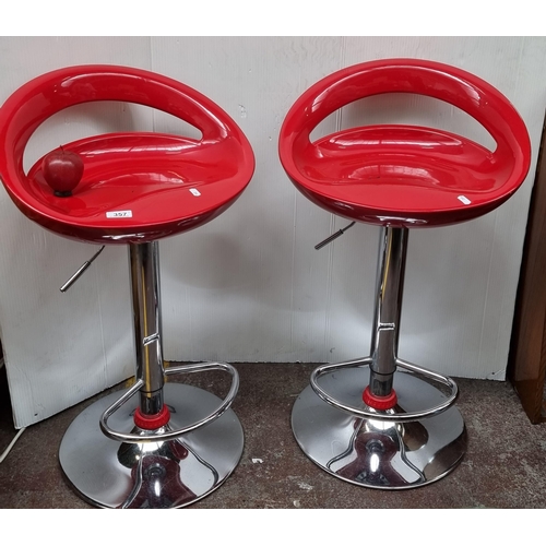 357 - A pair of adjustable hight barstools with moulded red seats and chrome base complete with footrest.