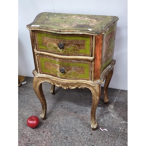 386 - A neatly sized, French style Florentine two drawer cabinet. Finished in green and gold, with round h... 