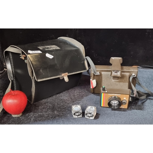 653 - A vintage Polaroid camera with two spare flash bulbs, in a case with a practical strap.