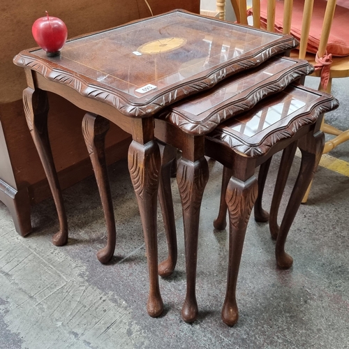 693 - A vintage set of three nesting tables, with glass tops. The largest table features a lovely inlay ca... 