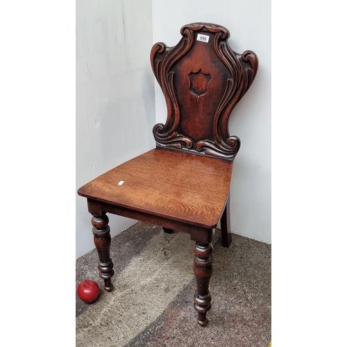 696 - A stunning example of a Victorian carved hall chair. The back features a central shield motif with s... 