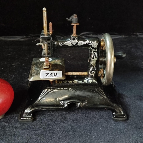 748 - A vintage, very heavy cast iron miniature sewing machine, with gilded floral decoration - a charming... 