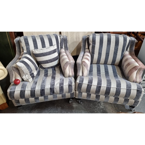 774 - A pair of generously proportioned armchairs, upholstered in a classic silver and charcoal striped pl... 