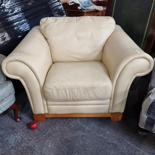 775 - A large and very generously proportioned armchair in a soft cream leather, with heavy wooden frame.