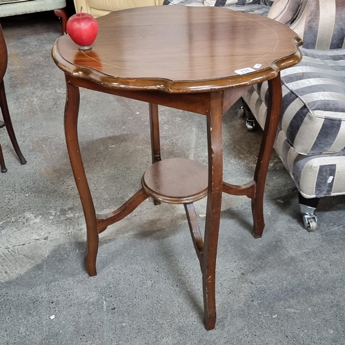 776 - An elegant Edwardian, two-tiered centre table with scalloped rim, string inlay and sabre legs.