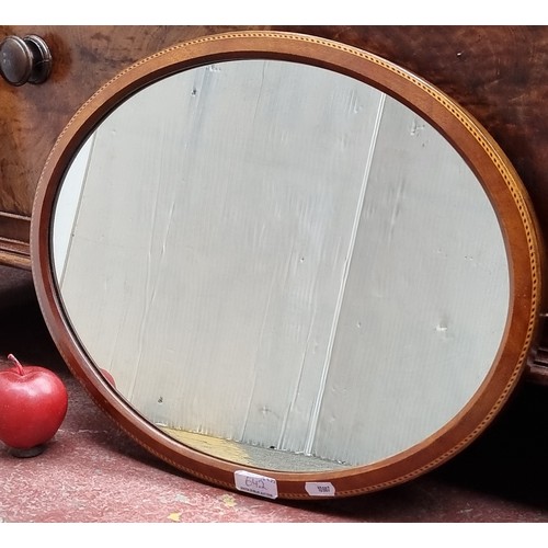 642 - An elegant example of an Edwardian wall hanging mirror in an oval shape with delicate string inlay a... 