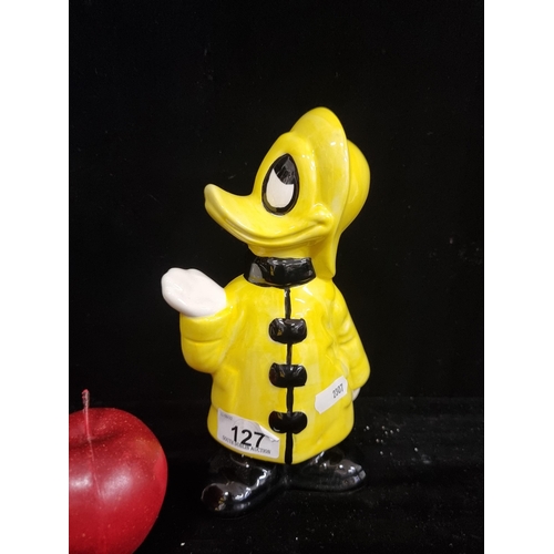 127 - A charming ceramic figure of Donald Duck dressed in a rain coat, holding his hand up to check for ra... 