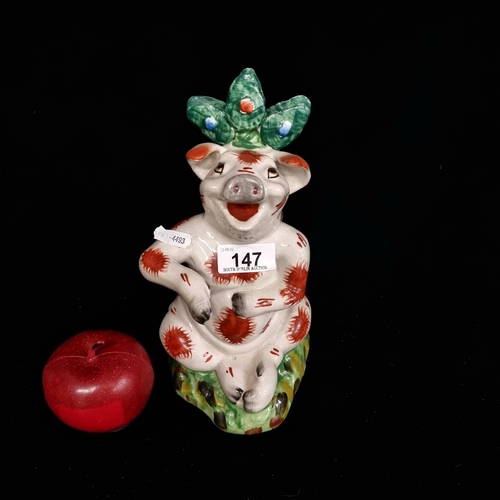 147 - A 19th century Staffordshire layback ceramic figurine of a cheerful pig, jauntily sitting against a ... 