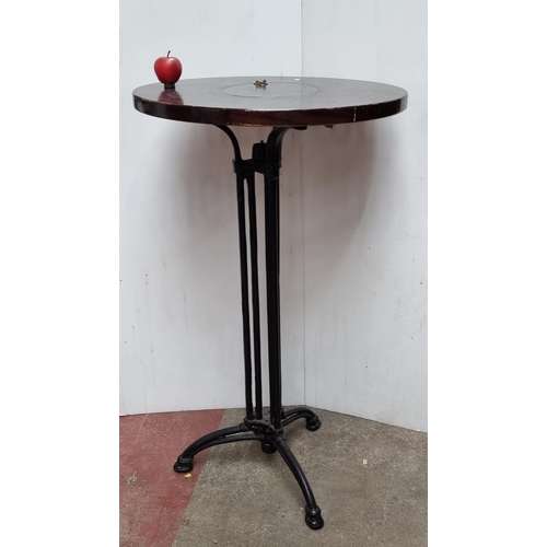 331 - A tall circular bar table with cast metal tripod legs and wooden top. This is a chest high table.