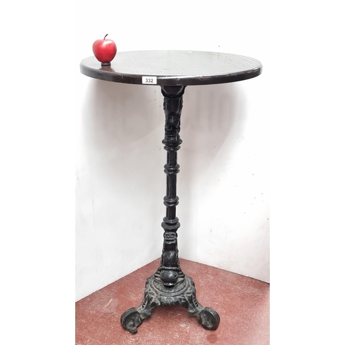 332 - An antique tall circular bar table with ornate cast iron base and wooden top. This is a chest high t... 