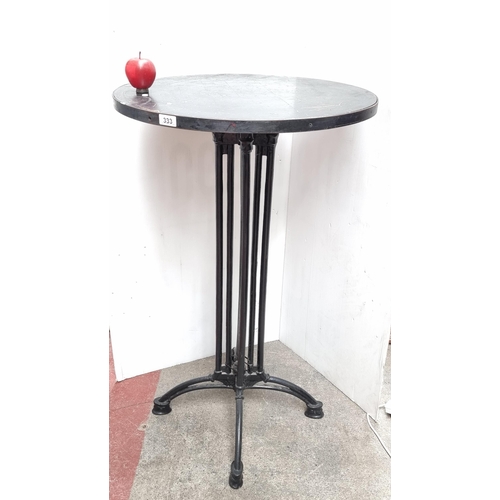 333 - A tall circular bar table with cast metal legs and wooden top. This is a chest high table.