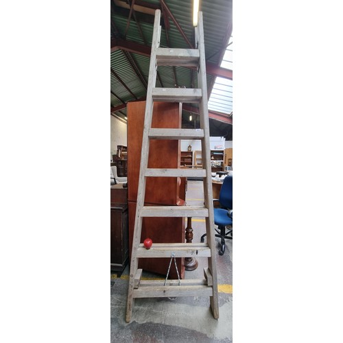 654 - A very good quality tall wooden A-frame ladder. 250 cm tall with seven steps.