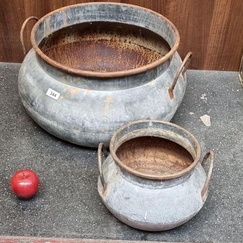 344 - Two antique cast metal cauldrons, including a large example and both equipped with original handles.... 