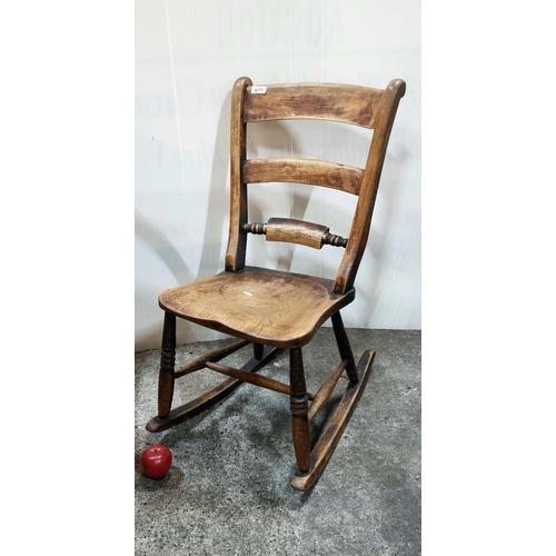 678 - An antique solid oak children's rocking chair with ladder back and turned wood bobbins.