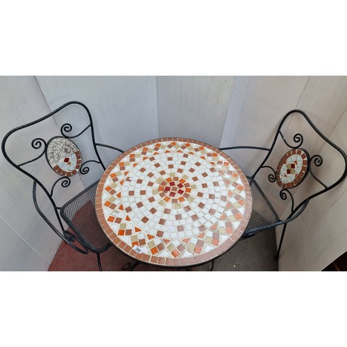 360 - A fabulous heavy outdoor dining set including circular wrought iron table with mosaic top and two wr... 