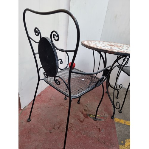 360 - A fabulous heavy outdoor dining set including circular wrought iron table with mosaic top and two wr... 