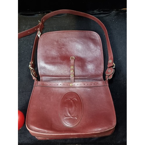 245 - A fabulous genuine leather satchel crossbody bag from Les Must de Cartier. In a maroon finish with p... 