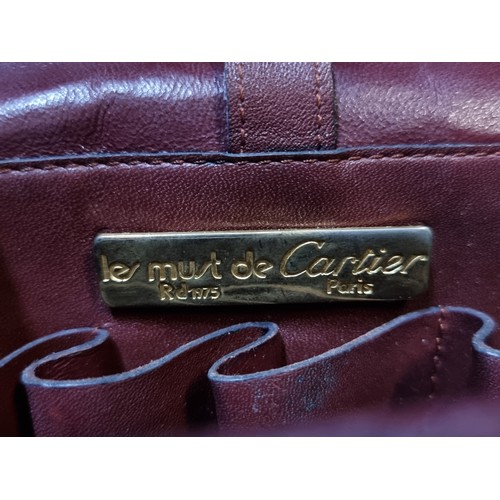 245 - A fabulous genuine leather satchel crossbody bag from Les Must de Cartier. In a maroon finish with p... 