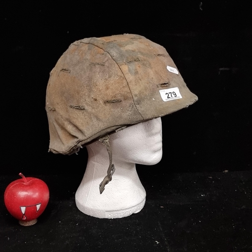 279 - An original 1970s Vietnam war M1C helmet, with straps and camouflage cover intact. A brilliant artef... 