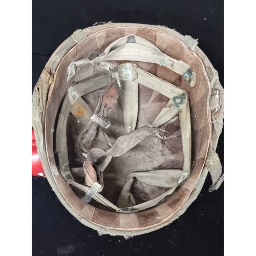 279 - An original 1970s Vietnam war M1C helmet, with straps and camouflage cover intact. A brilliant artef... 