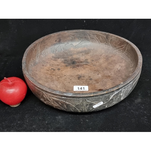 141 - A very large, lathe turned. African wooden bowl. With incised detail featuring elephant and rhinocer... 