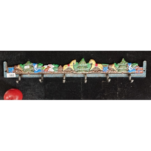 162 - A fabulous cast metal wall-mounting coat rack. Featuring a festive scene of present opening and Chri... 