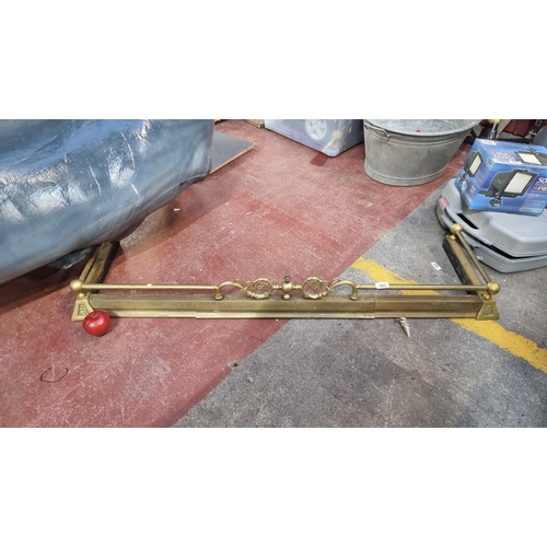383 - A vintage, brass fire fender. With foliate scroll detail and ball joints. Internal measurements: L12... 