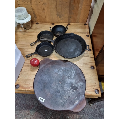 555 - A selection of five, cast iron cookware items. Including two fried egg pans with a large stoneware P... 