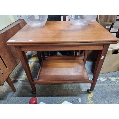 589 - A very attractive mid-century two tier drinks trolley, held on castors by EastCraft Scotland. Folds ... 