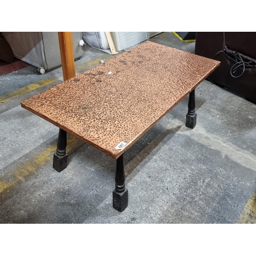 687 - A very stylish hand hammered copper coffee table with ebonised turned legs. H39cm x L87cm x D45cm