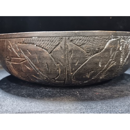 141 - A very large, lathe turned. African wooden bowl. With incised detail featuring elephant and rhinocer... 