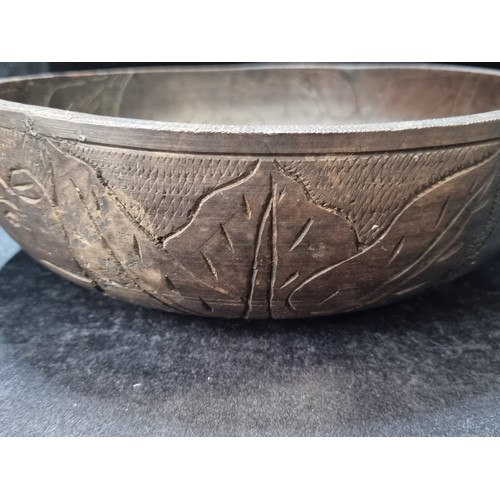 141 - A very large, lathe turned. African wooden bowl. With incised detail featuring elephant and rhinocer... 