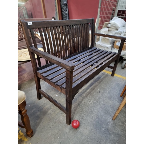 454 - A classic wooden three seater garden bench with high arms, slatted back and a lovely dark stained fi... 