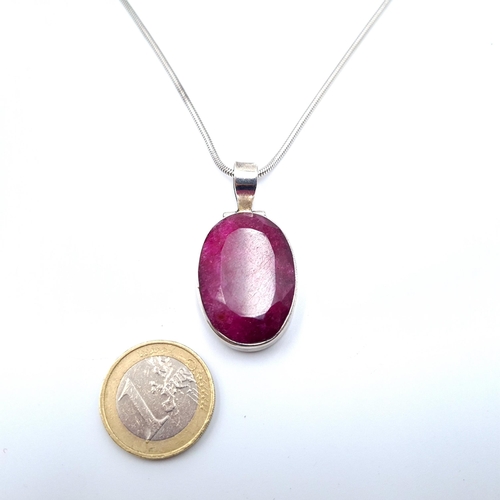 547 - A striking facet cut oval Ruby stone pendant, set in sterling silver with a sterling silver chain. L... 