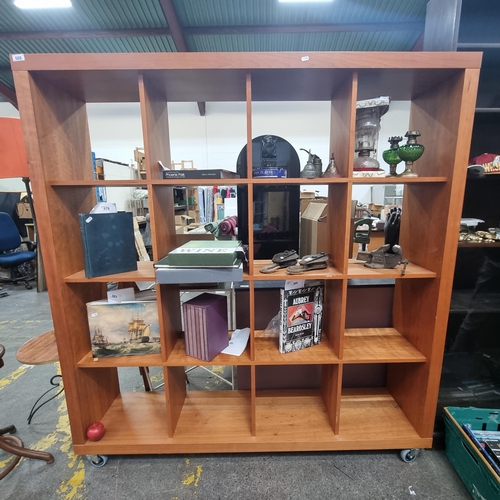 588 - A very handsome, mobile, wooden shelving unit. A square frame example with sixteen box shelves for a... 