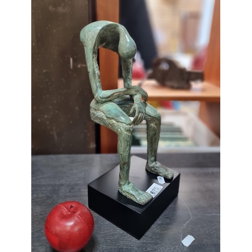 675 - A fabulous heavy cast bronze sculpture of a stylised figure, suspended in a slumped seated pose, sup... 