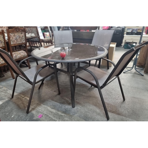 761 - A high quality circular outdoor dining table with a sleek grey frame, tempered glass top and four ma... 