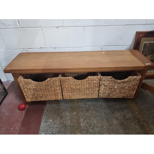 772 - A solid oak storage bench with three pull out wicker baskets to base. A classic heavy piece in very ... 