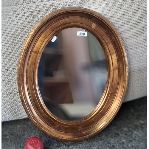 820 - A oval wall mirror with a lovey gold toned frame.